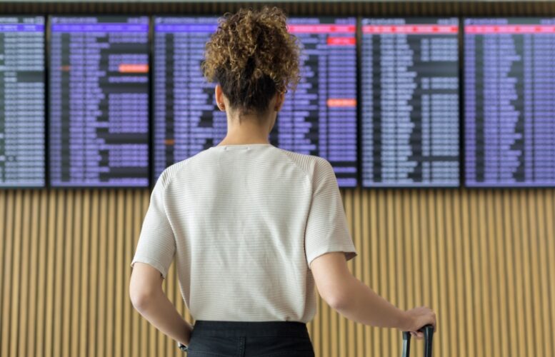 Woman checking flight departure boards at airport