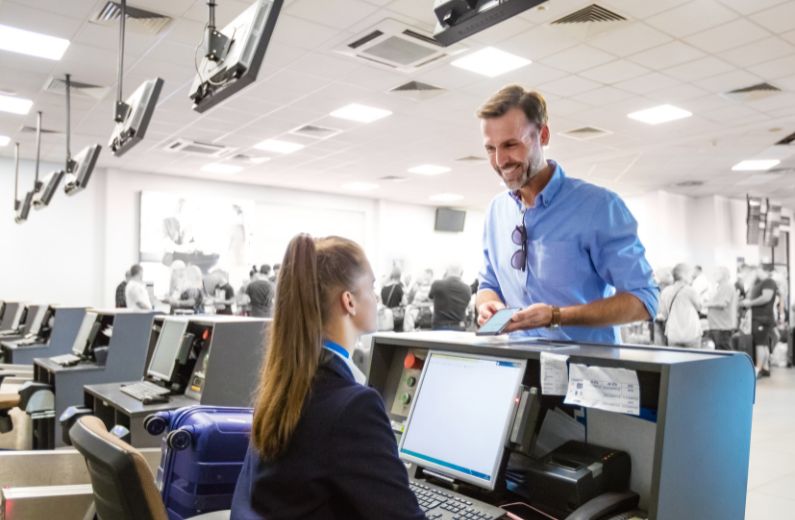 Man in blue shirt checking in for flight at airport check in desk